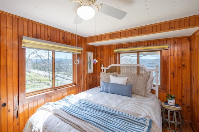 bedroom with a ceiling fan and wooden walls
