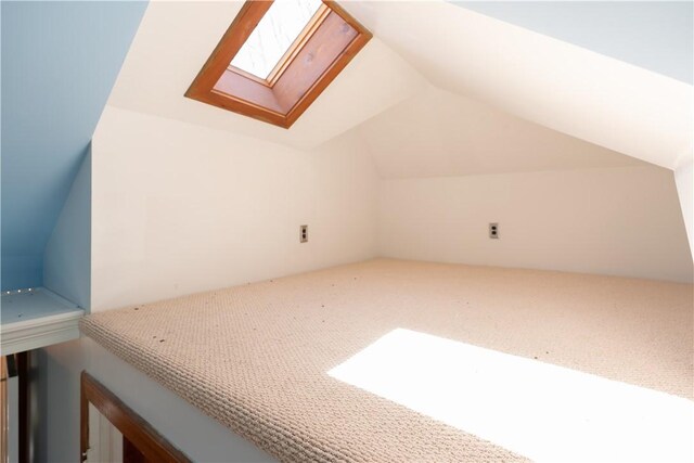 bonus room with lofted ceiling with skylight and carpet floors