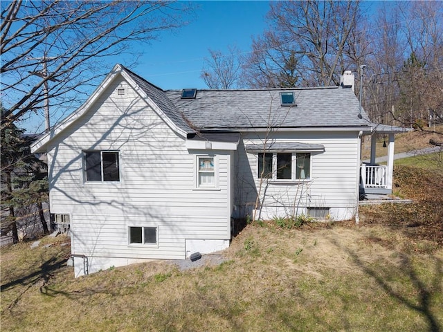 back of property featuring a yard and a shingled roof