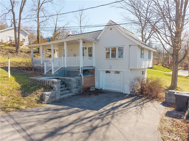 view of front of house with driveway, roof with shingles, stairs, and covered porch