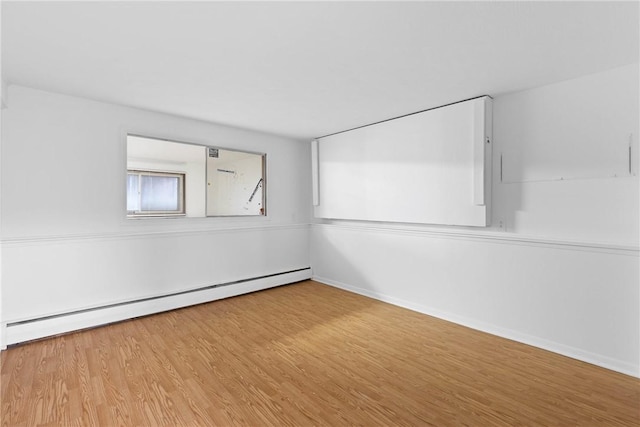 spare room featuring a baseboard radiator, wood finished floors, and baseboards