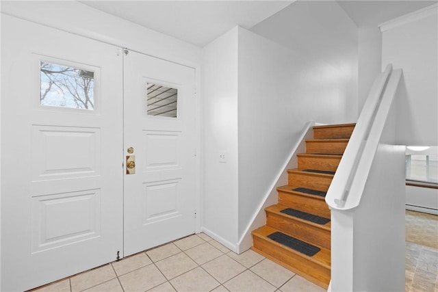entryway featuring baseboards, light tile patterned flooring, stairway, and a healthy amount of sunlight