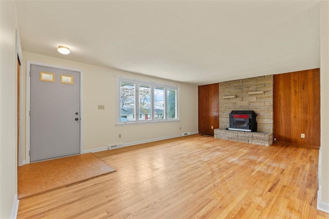 unfurnished living room featuring baseboards, visible vents, a fireplace, and light wood-style floors