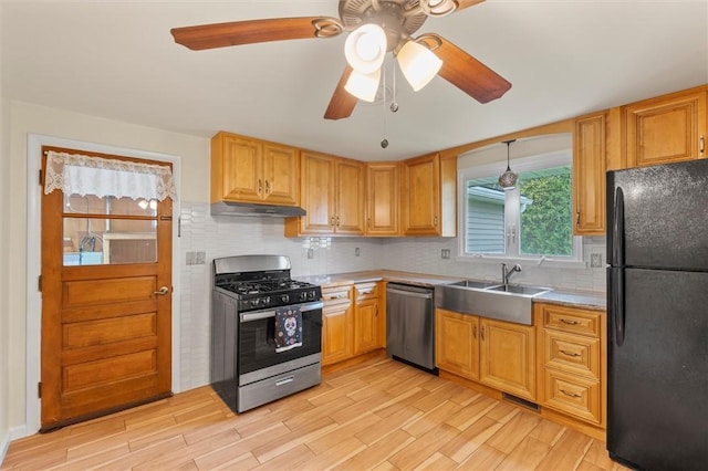 kitchen featuring a ceiling fan, stainless steel appliances, light wood-type flooring, and a sink