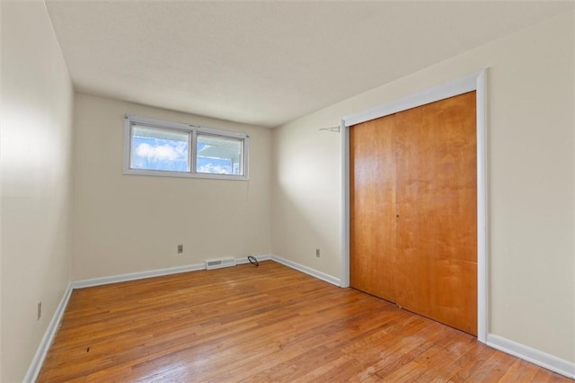 unfurnished bedroom with baseboards, visible vents, light wood finished floors, and a closet