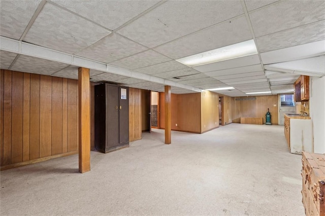 finished basement with wooden walls and a paneled ceiling