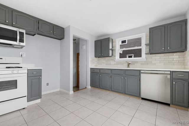 kitchen with gray cabinets, backsplash, white appliances, and light countertops
