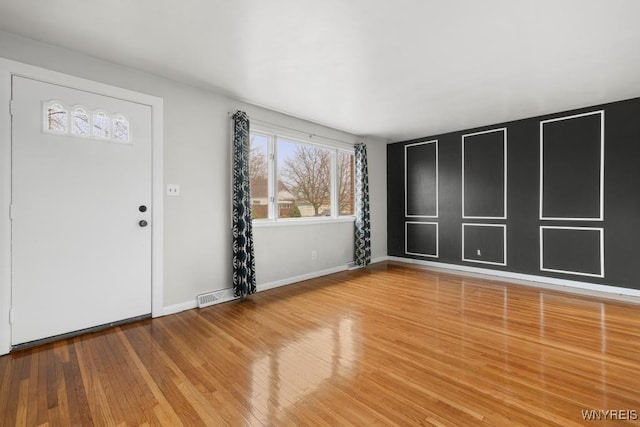 foyer entrance featuring visible vents, baseboards, and wood finished floors