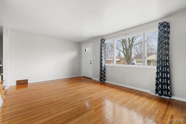 unfurnished living room featuring visible vents, light wood finished floors, and baseboards
