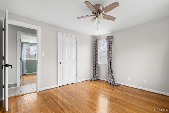 unfurnished bedroom with visible vents, hardwood / wood-style flooring, baseboards, and multiple windows