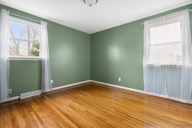 empty room featuring visible vents, baseboards, and wood finished floors