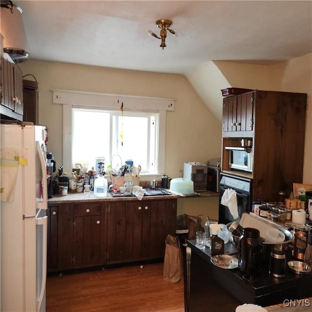 417 Otsego St, German Flatts, NY 13357 - kitchen featuring stainless steel microwave, dark brown cabinets, freestanding refrigerator, light wood-style floors, and black oven