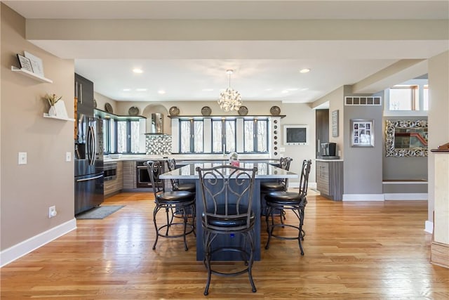 4872 Bedford Dr, Canandaigua-Town, NY 14424 - dining area with light wood-style flooring, a healthy amount of sunlight, baseboards, and a notable chandelier