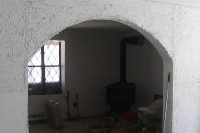 interior space with arched walkways and a wood stove