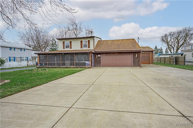 view of front facade featuring concrete driveway, an attached garage, fence, a front yard, and a sunroom