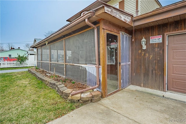 property entrance featuring a lawn and fence