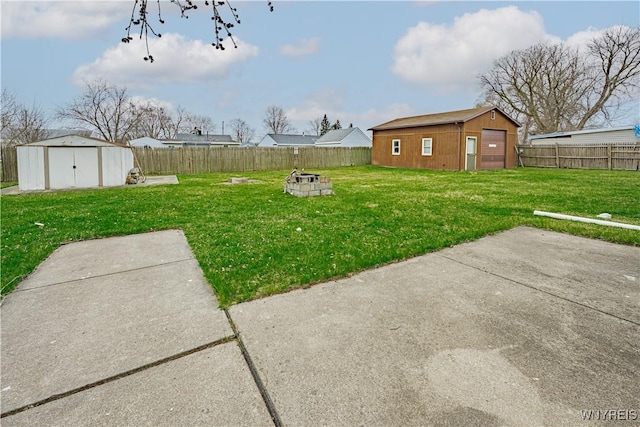 view of yard featuring a fire pit, an outbuilding, a shed, and a fenced backyard