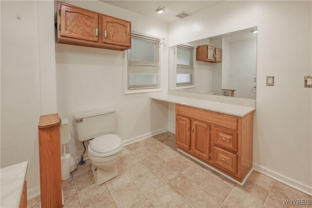 bathroom featuring baseboards, visible vents, vanity, and toilet