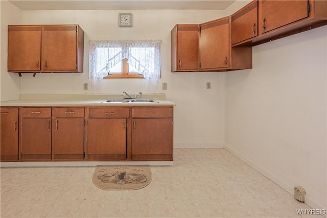 kitchen featuring light floors, brown cabinetry, light countertops, and a sink