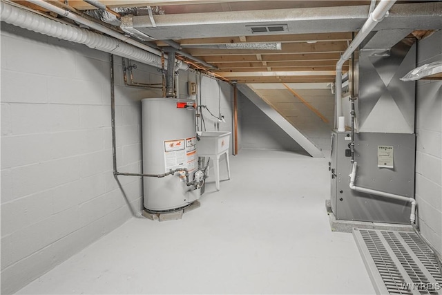 unfinished basement with concrete block wall, heating unit, visible vents, and gas water heater