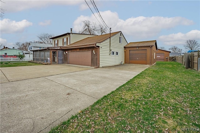 view of property exterior with fence, an attached garage, driveway, a lawn, and a sunroom