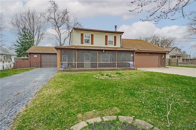 view of front of house featuring fence, an attached garage, a sunroom, a front yard, and aphalt driveway