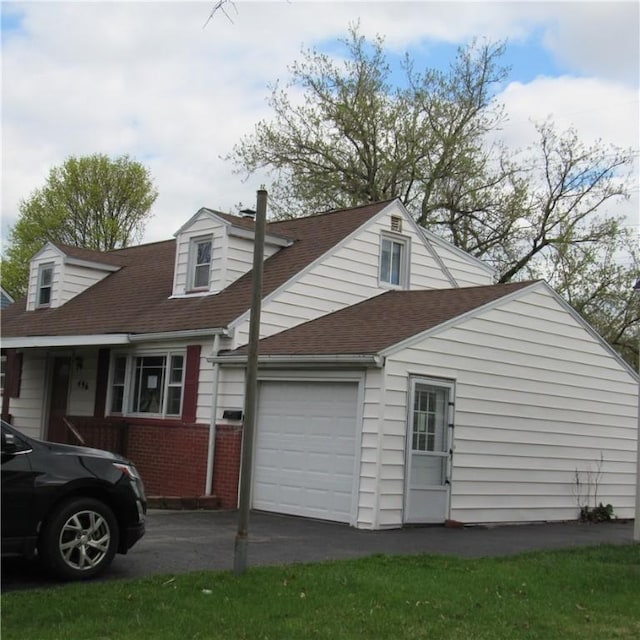 view of side of property with a garage, brick siding, concrete driveway, and roof with shingles