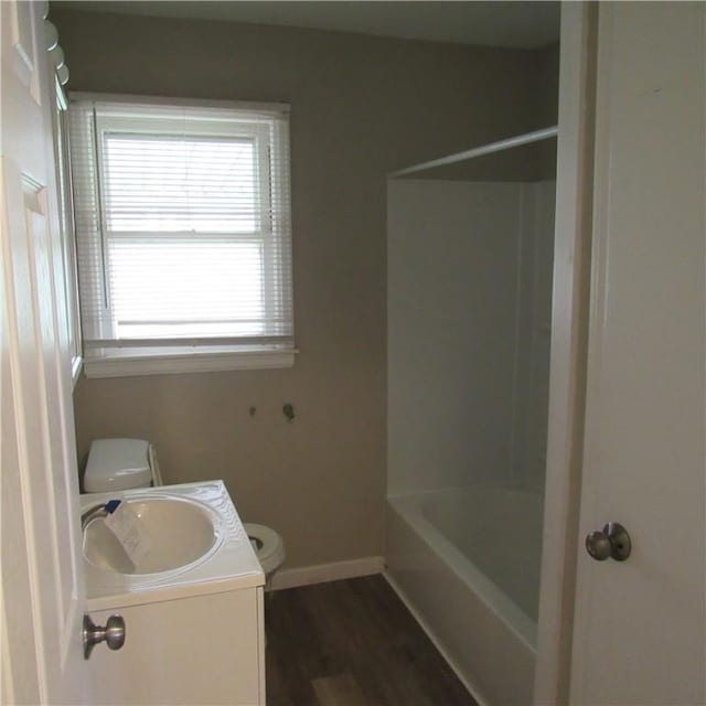 bathroom featuring washtub / shower combination, baseboards, toilet, wood finished floors, and vanity