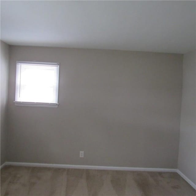 unfurnished room featuring light colored carpet and baseboards