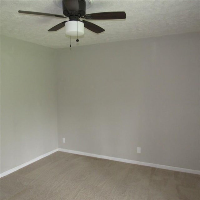 empty room featuring a textured ceiling, a ceiling fan, light carpet, and baseboards