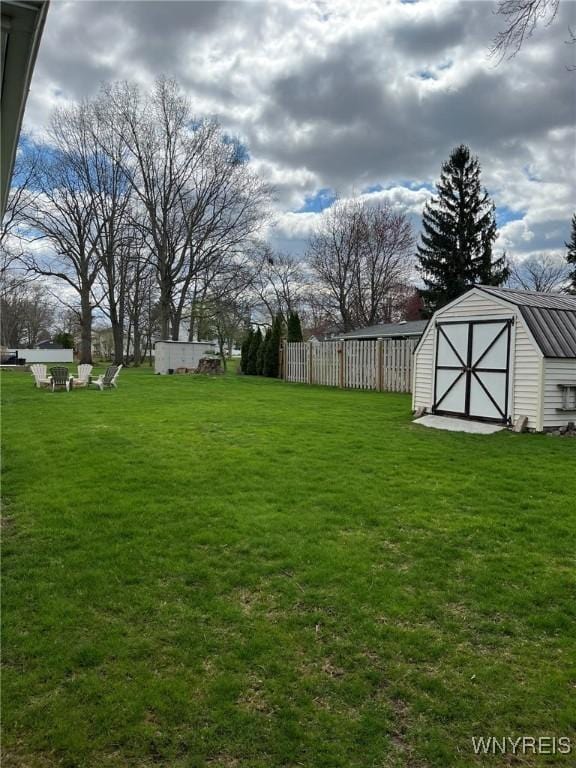 view of yard with an outdoor structure, a shed, and fence