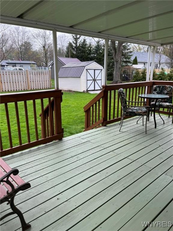 deck with an outbuilding, a shed, and a lawn