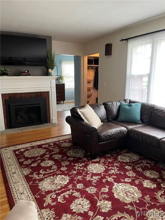 living area with a brick fireplace, wood finished floors, and plenty of natural light