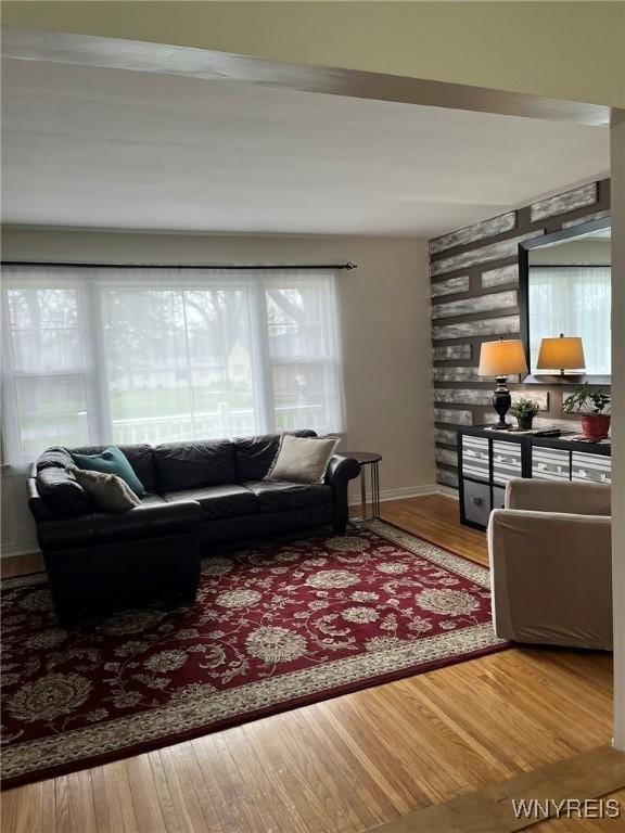 living room featuring baseboards, wood finished floors, and an accent wall