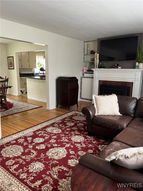 living area with light wood finished floors and a brick fireplace