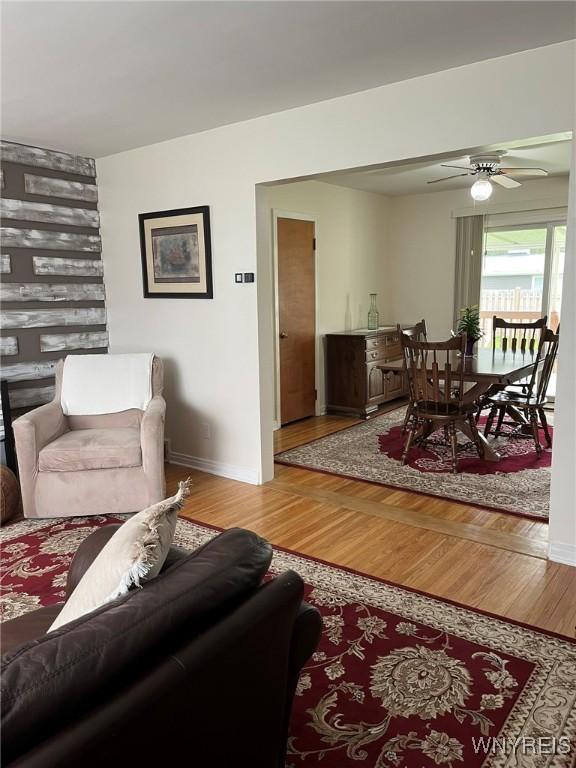 living area with baseboards, wood finished floors, and ceiling fan