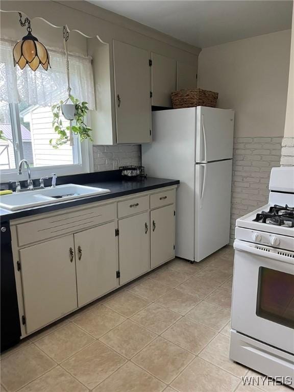 kitchen featuring backsplash, dark countertops, light tile patterned floors, a sink, and white appliances