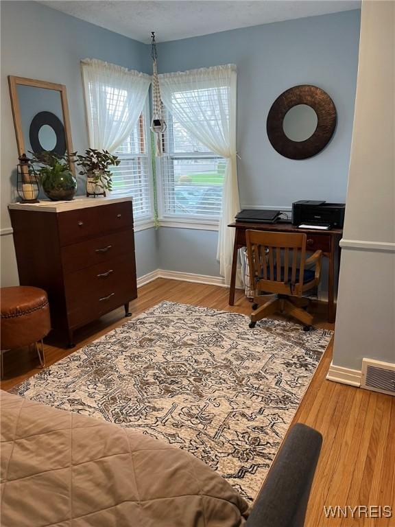 living area with baseboards, wood finished floors, and visible vents