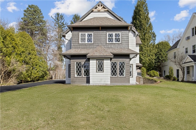 rear view of house with a shingled roof and a yard