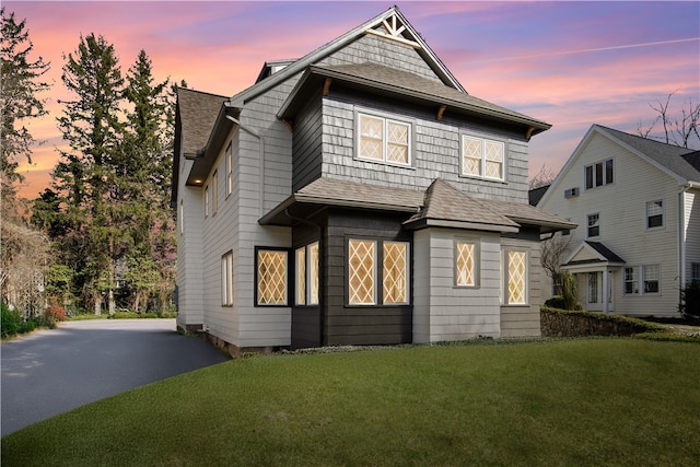 traditional home with a lawn, a shingled roof, and driveway