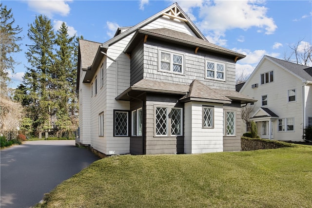 traditional-style home featuring roof with shingles and a front yard