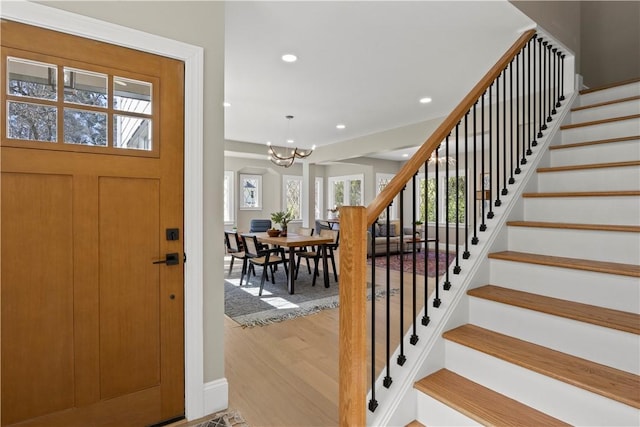 foyer entrance featuring a notable chandelier, wood finished floors, stairs, and recessed lighting