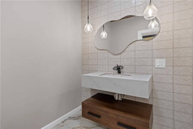 bathroom featuring marble finish floor, baseboards, and a sink
