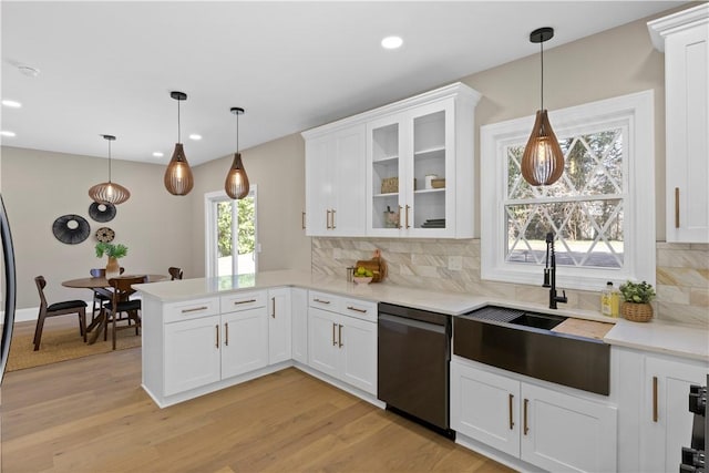 kitchen with dishwasher, backsplash, a peninsula, and a sink
