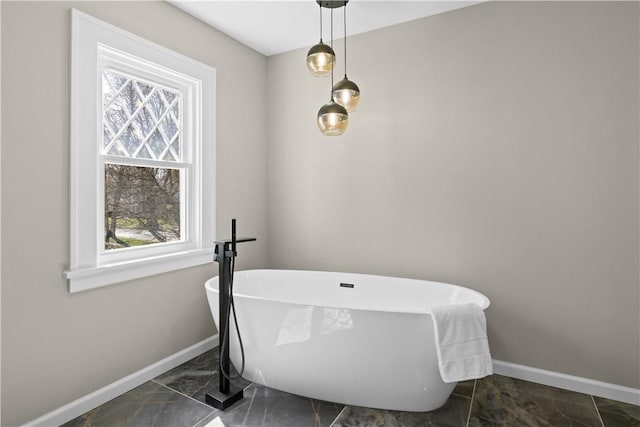 full bathroom featuring a soaking tub, a wealth of natural light, and baseboards