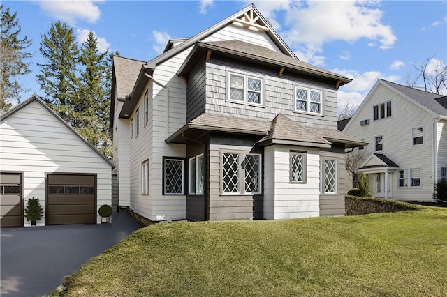 traditional-style house featuring a front lawn, an outdoor structure, roof with shingles, and a detached garage