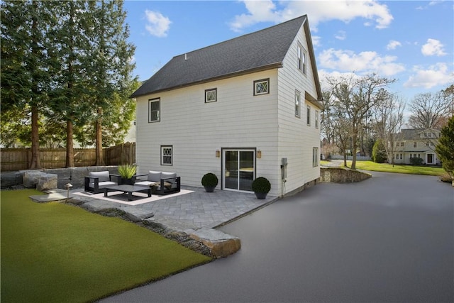 back of property with a lawn, fence, an outdoor living space, and a patio area