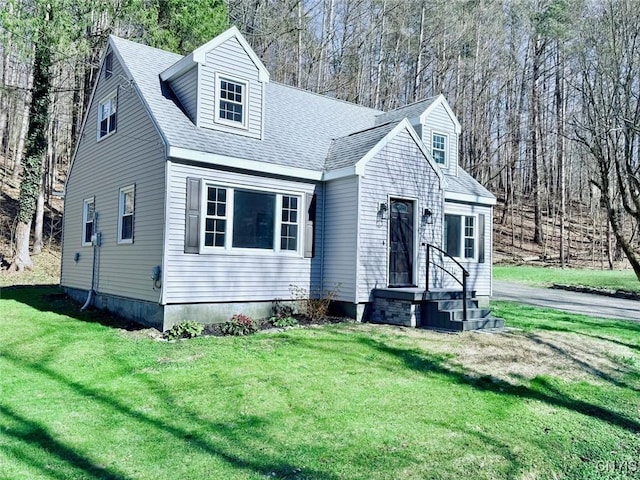 cape cod home featuring roof with shingles and a front yard