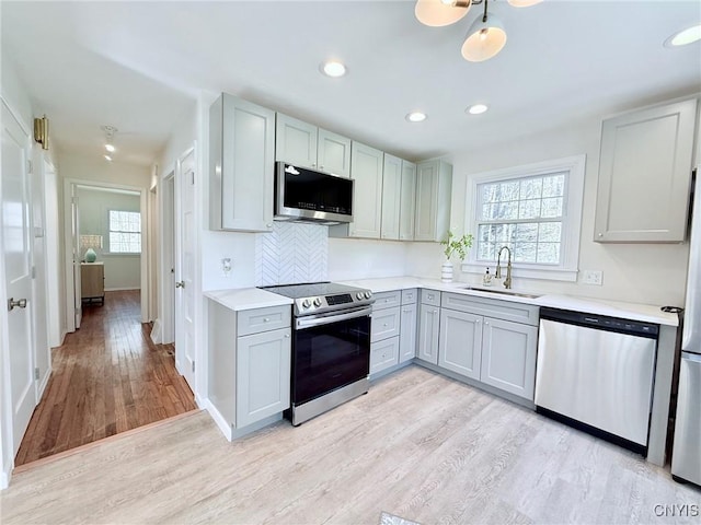 kitchen featuring light wood-style floors, a healthy amount of sunlight, stainless steel appliances, and a sink