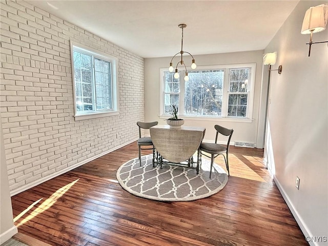 dining space featuring brick wall, a wealth of natural light, visible vents, and dark wood-style floors